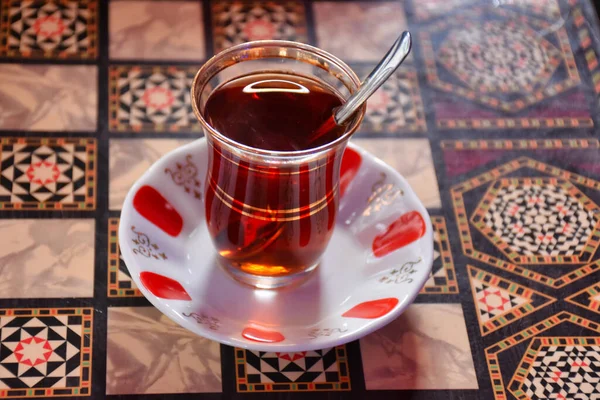 スプーン付きの伝統的なガラスカップのトルコ茶は 酔うのを待っているバックギャモンテーブルに立っています — ストック写真
