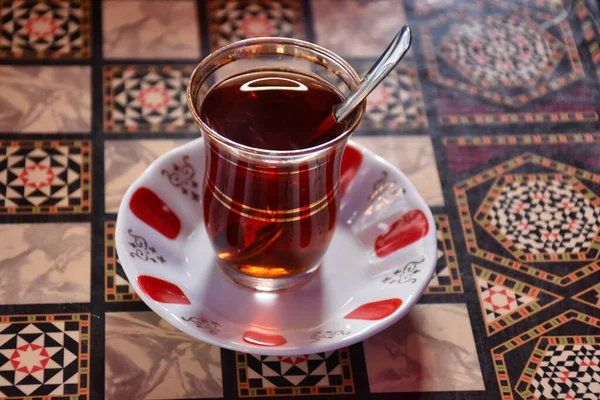 スプーン付きの伝統的なガラスカップのトルコ茶は 酔うのを待っているバックギャモンテーブルに立っています — ストック写真