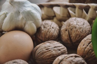 Fresh village egg, shelled walnuts and a head of garlic in a wicker basket. Healthy eating food low carb keto ketogenic diet meal plan protein fat.