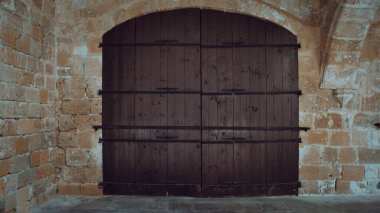 Medieval Brown Wooden Door in Stone Wall. Old castle stone wall with big wooden doors. Retro wooden doors castle rock, great design for wallpaper