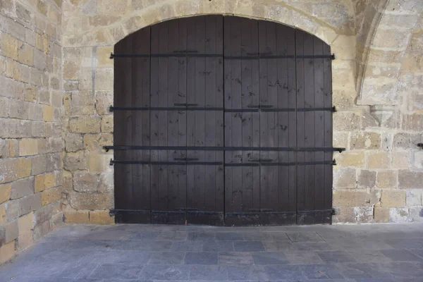 Medieval Brown Wooden Door in Stone Wall. Old castle stone wall with big wooden doors. Retro wooden doors castle rock, great design for wallpaper