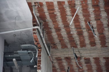 Brick room walls and ceiling view of a being demolished building with electricity, water and ventilation installations. Destroyed building, can be used as demolition, earthquake, bomb, terrorist attack or natural disaster