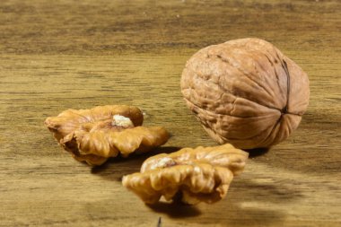 heaps of walnuts, one of which has been opened, waiting to be eaten on a wooden table