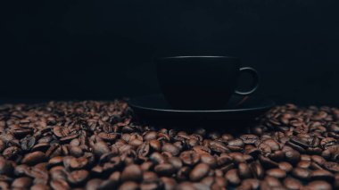 a black Coffee cup isolated on the beans. Espresso cup on black background and glowing coffee beans on it. coffee love, addiction