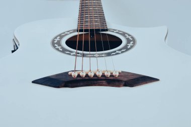 Front surface close-up of a white electric acoustic guitar isolated on a white background