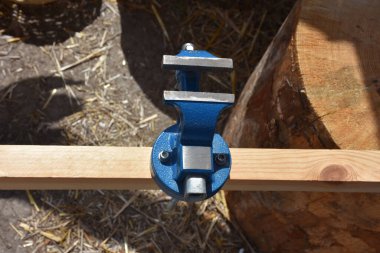 Carpenter's tools on wooden plank, iron vise in work area. iron vise and press detail. Bench vise attached to a worktop