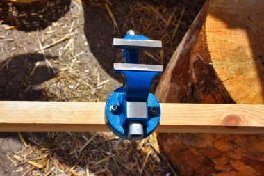 Carpenter's tools on wooden plank, iron vise in work area. iron vise and press detail. Bench vise attached to a worktop