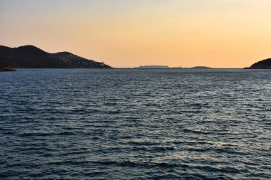 Gün batımında karanın içe doğru kıvrıldığı geniş bir deniz koyunun kıyı manzarası.