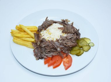  doner kebab with rice, fried potatoes, tomatoes and pickled cucumbers served on a white plate