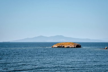 A Small islet, cliffs, mountain and bay view in the virgin bays of izmir Foca. Virgin coves of the Aegean Sea. Phokaia, Izmir Bays.The view of the Karaburun mountains and the Aegean Gulf from Foca.
