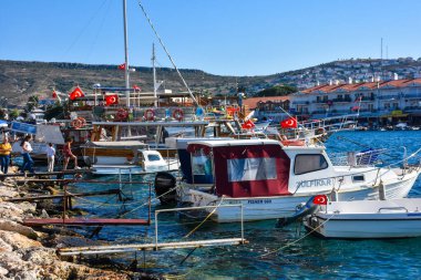 Foca, izmir, Turkey  29 Jun 2021. Wooden boats in the harbor in Foa, people looking at the sea, tour boats, Turkish flags and restaurants, mountains  across 