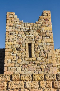 Detailed stone walls of a ruined old medieval castle and a clear sky behind it
