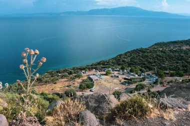 Visitors to the ancient city of Assos park their vehicles on the slope of the mountain and enjoy the magnificent view of Edremit bay in Aegean Turkey