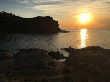 Gökçeada Imbros adasındaki Yıldizkoy plajından günbatımı, dalgalar ve volkanik dağ manzarası. Çanakkale Türkiye