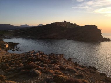 Gökçeada Imbros adasındaki Yıldizkoy plajından günbatımı, dalgalar ve volkanik dağ manzarası. Çanakkale Türkiye