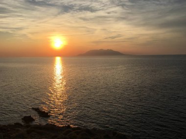 Çanakkale 'deki Imbros Gökçeada' daki Yıldırım Sahili 'nden gün batımında Semendirek Adası' nın uzak manzarası