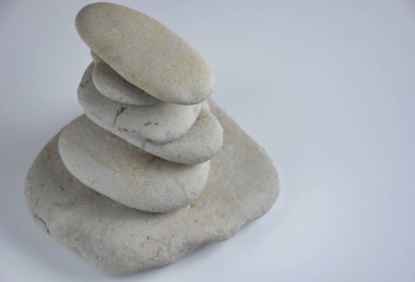 Beyaz arka planda üst üste dizilmiş beyaz taşlar. Spa taşları spa, meditasyon ve maneviyat için kullanılabilir.