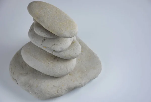 White stones stacked in a row on a white background. Spa stones Can be used for spa, meditation and spirituality