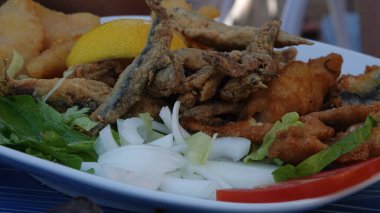  Kızarmış ançüez, mezgit, dilimlenmiş soğanlı limonlu roka. Balık ve patates kızartması