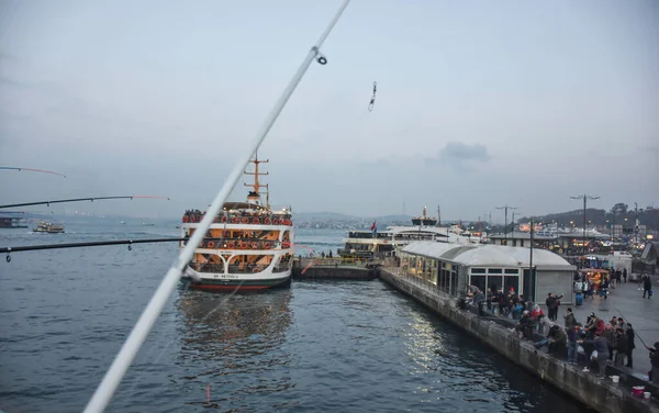 stock image Istanbul, Turkey 11.25.2019 The ferry that picks up its passengers at Karaky Pier in Istanbul and the fishing rods of the fishermen on the Galata Bridge