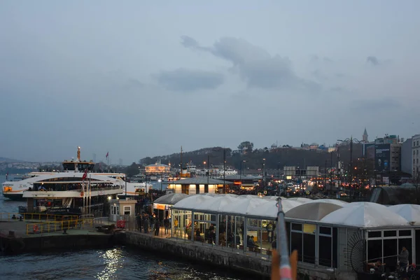 İstanbul, Türkiye 11.25.2019 İstanbul 'daki Karaky İskelesi' nden yolcularını alan feribot ve Galata Köprüsü 'ndeki balıkçıların oltaları