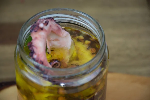 Close up view of sliced octopus marinated in olive oil in a glass jar