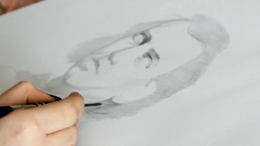 Beyaz bir kağıda kurşun kalemle bir adamın portresini çizen genç bir adamın yakın plan görüntüsü. Piyanist müzisyen Johannes Brahms 'ın Portresi. 