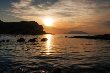 Gün batımında Imbros Adası 'ndaki Yildizkoy (Arcadia) plajından gökyüzü bulutlu Semendirek adası manzarası. Gökçeada, anakkale Türkiye