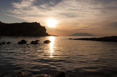 Gün batımında Imbros Adası 'ndaki Yildizkoy (Arcadia) plajından gökyüzü bulutlu Semendirek adası manzarası. Gökçeada, anakkale Türkiye