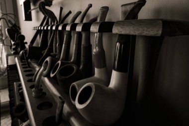 Ahşap bir stantta sigara içmek için eski bir boru koleksiyonu. Eski tütün boruları.