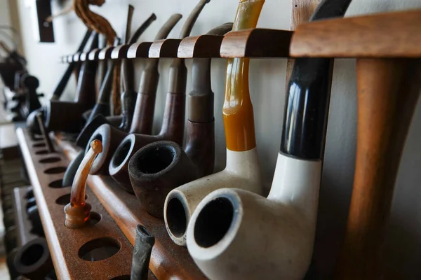 Ahşap bir stantta sigara içmek için eski bir boru koleksiyonu. Eski tütün boruları.