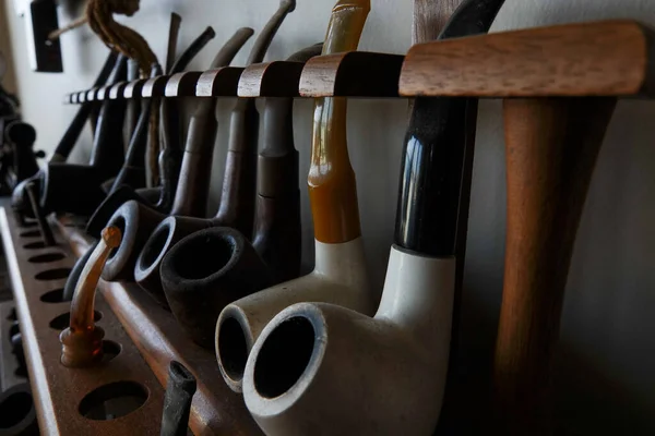 Stock image A collection of old briar pipes for smoking on a wooden stand. Old tobacco pipes.