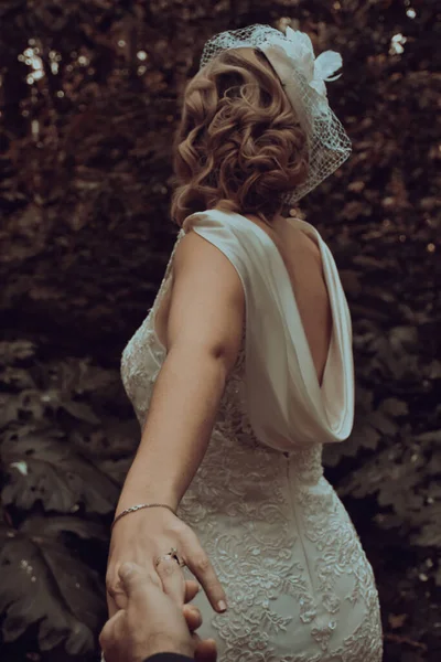 去年秋天 新娘穿着老式的婚纱在森林里背着新郎 牵着新郎的手 — 图库照片