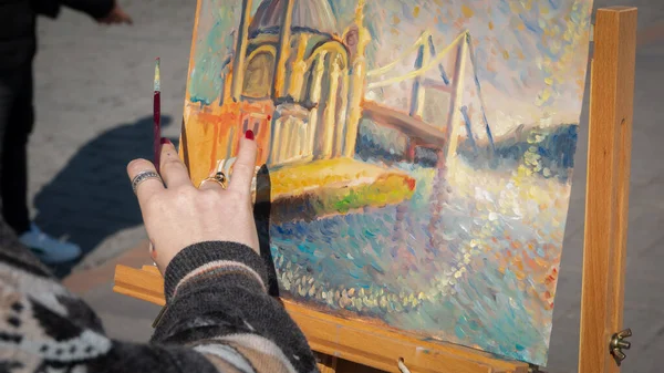 Young woman plein painter painting Grand Ortakoy mosque in squere of Ortakoy, Istanbul Turkey