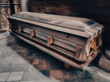 Cenazeden ya da mezarlığa gömülmeden önce kilisede ya da cenaze evinde üzerinde altın süslemeler bulunan metal bir tabutun yakın çekimi.