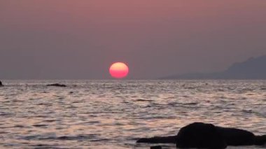 Gökceada, Imbros Adası 'nın gün batımı manzaralı dağlarla deniz dalgaları ve karşı adanın Semendirek' i. Arcadia Kardamos bölgesi. 4K talebi. Gün batımını hızlandıran sahildeki deniz ve dağ manzarası.  