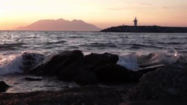 Kalekoy limanı Gkeada 'dan Semendirek Adası' na doğru deniz manzaralı günbatımı manzaralı. Deniz fenerinin yanında yavaşça yürüyen bir adam. Çanakkale Türkiye 'si.