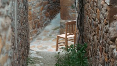 Gliki 'deki eski bir Yunan köyü olan Gkceada, Imvros anakkale, Türkiye' deki eski taş evler arasındaki dar yolda tahta bir sandalye. 