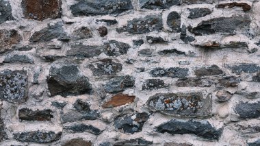 old stone wall background in various colors. The wall of the old historical stone house built with stones one by one