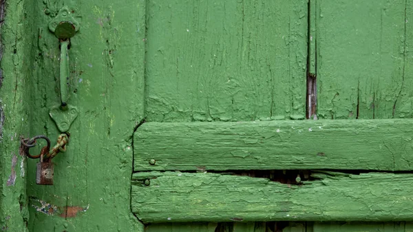 An old wooden door painted green with a rusty padlock on it. copy space vintage wallpaper