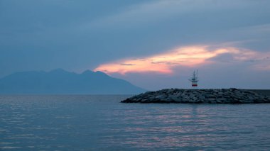 İlkbaharda yeşil dağları ve deniz feneriyle Gökçeada Kalekoy liman manzarası