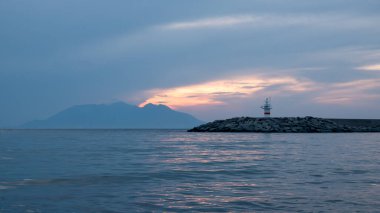 Günbatımı, Yunan adası Semendireği ve Gökçeada Kalekoy 'daki deniz feneri manzarası. Imbros Adası Canakkale, Türkiye