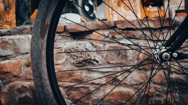 Bisiklet tekerleği ve taş bir duvarın önündeki jantların yakın plan görüntüsü. Klasik duvar kağıdı.