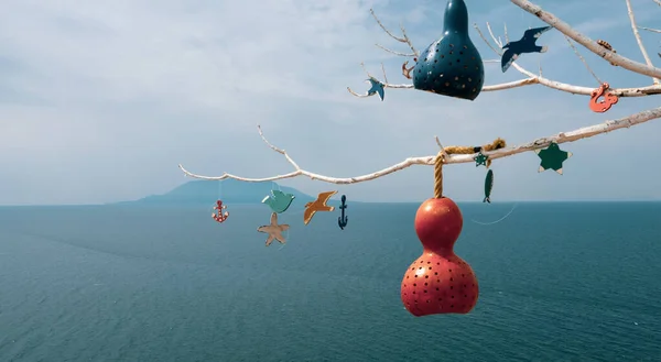 Decorative pumpkin lamps hanging on tree branches against the North Aegean sea. Samothrace island in the background. Calabash lamp interior decoration is made of dry pumpkins