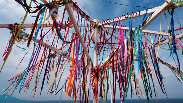 Colorful traditional wish ribbons tied to an iron pole tree in Kalekoy, Gokceada. Many multi-colored ribbons fluttering in the wind.