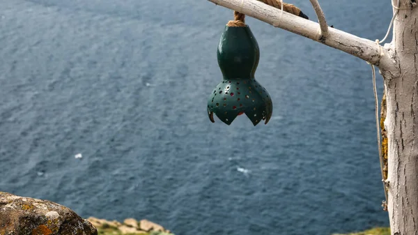 Decorative pumpkin lamp hanging on tree branches against the North Aegean sea. Samothrace island in the background. Calabash lamp interior decoration is made of dry pumpkins