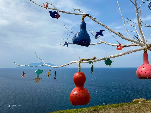 Gourd lamps hanging on tree branches against to Gokceada Kalekoy harbour.  Decorative gourds pumpkin.  Calabash lamp exterior decoration is made of dry pumpkins