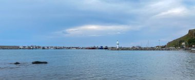 Kalekoy deniz feneri ve Gökceada Imbros Adası Kalekoy limanının gün batımında sahil manzarası. Çanakkale, Türkiye