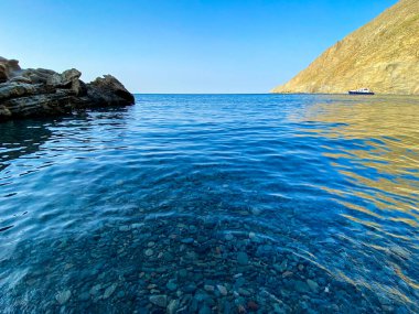 Gökceada Yıldız Körfezi 'nin yanındaki Blue Bay (Mavi Koy) deniz manzarası ve körfeze demirlemiş bir tekne. Imbros Adası, Canakkale, Türkiye