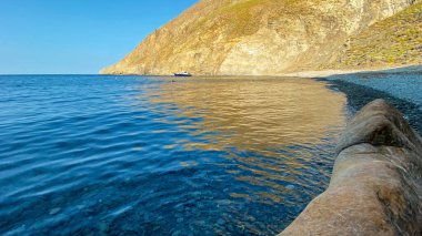  Gökceada Yıldız Körfezi 'nin yanındaki Blue Bay (Mavi Koy) deniz manzarası ve körfeze demirlemiş bir tekne. Imbros Adası, Canakkale, Türkiye